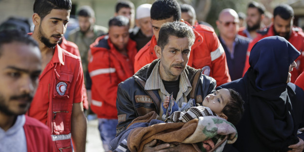A Syrian man carries a child after evacuating from the Eastern Ghouta enclave into the government side of the Wafideen checkpoint on the outskirts of the Syrian capital Damascus on March 14, 2018. / AFP PHOTO / LOUAI BESHARA (Photo credit should read LOUAI BESHARA/AFP/Getty Images)